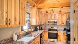 Una cocina con gabinetes de madera, encimeras de granito, electrodomésticos de acero inoxidable y piso de baldosas de piedra.