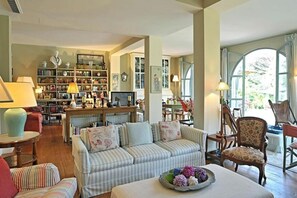 Relax in a comfortable seating area with a sofa and armchair, surrounded by a bookshelf filled with books and decorative items.