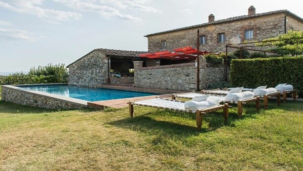 A stone building with a swimming pool and outdoor seating.