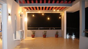 An outdoor patio area with a tiled floor, potted plants, string lights, and a view of the night sky. - Hary's aparthotel (Toliara)