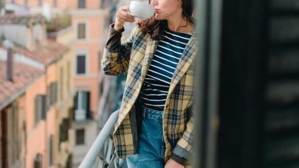 A person standing on a balcony with a cityscape in the background. - ONEBEDROOM APARMENT (Roma)
