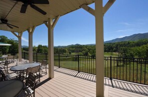 A covered outdoor patio with tables and chairs, a view of a green landscape with trees and mountains in the distance. - Mountain Views! Golf & Pool Min to Cades Cove (Townsend)