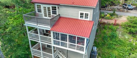Et toetagers hus med rødt tag, en balkon på øverste etage, og en trappe op til øverste niveau.