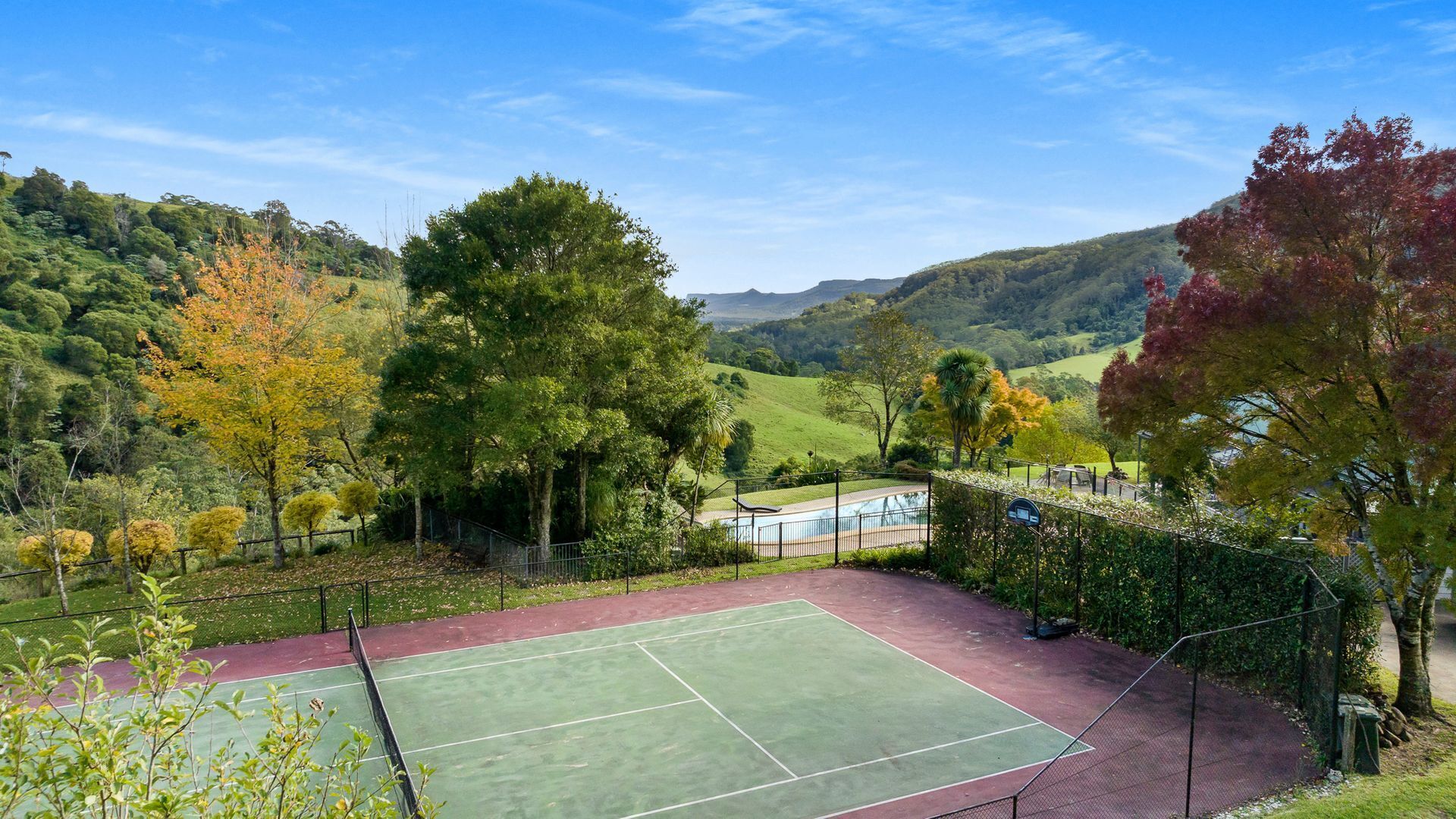 Una cancha de tenis rodeada de exuberante vegetación y colinas.