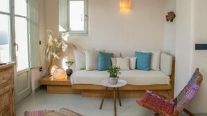 Un salon chaleureux avec un canapé, un luminaire suspendu en fibres tressées, un fauteuil et une petite table.