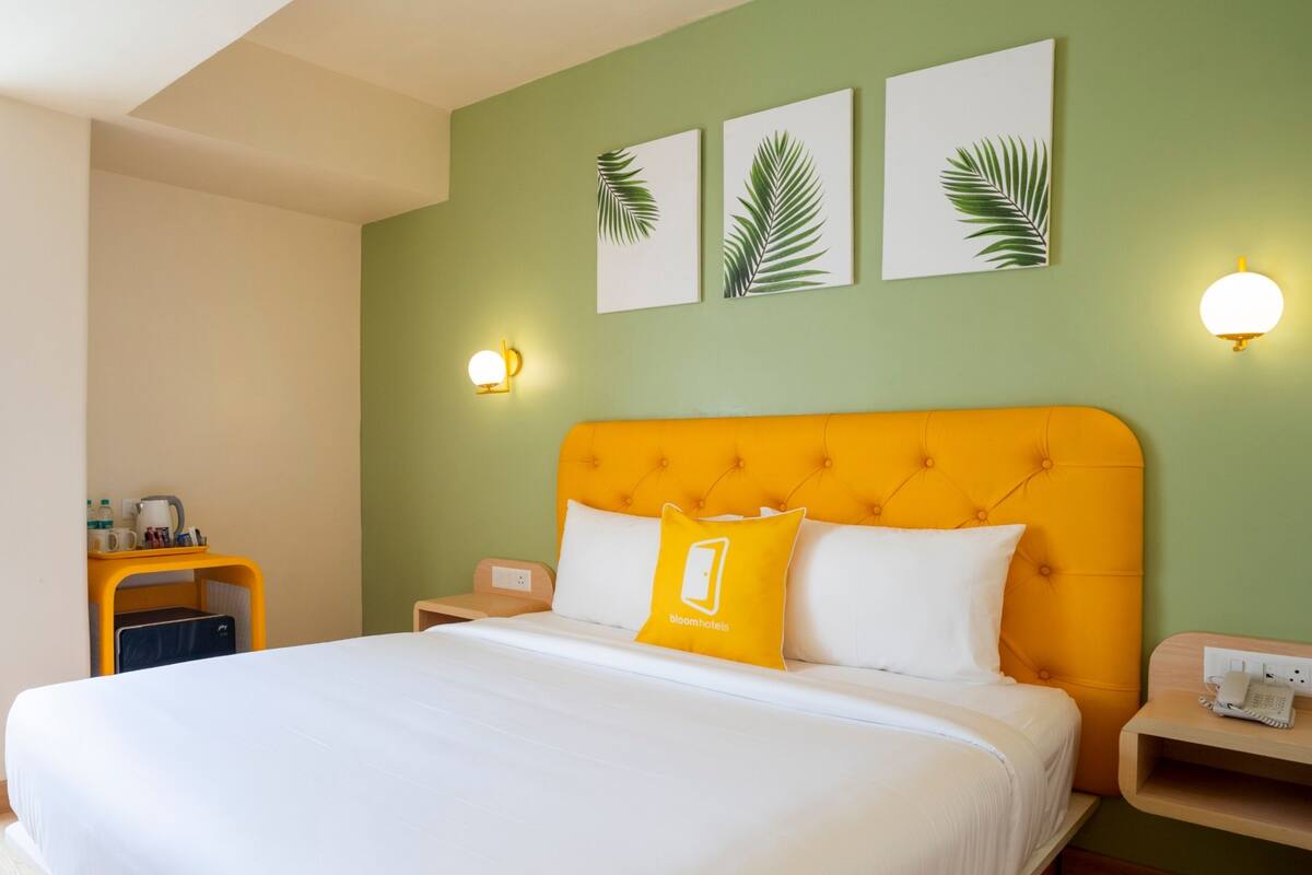 A hotel room with a large bed, a nightstand, a bedside table, and a wall-mounted lamp.