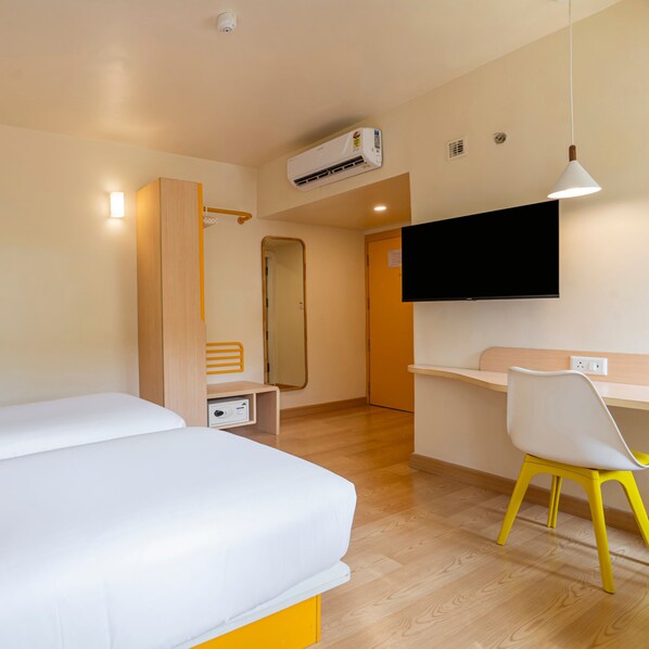 Habitación de hotel con cama, escritorio con silla, televisor montado en la pared y equipo de aire acondicionado.