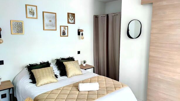 Ein modernes Schlafzimmer mit Bett, Nachttisch, Spiegel und Wandbildern.