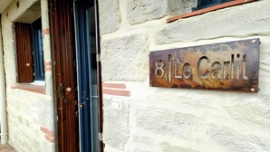 A building facade with a weathered metal sign reading "8 Le Carlit" and two wooden doors with metal handles.