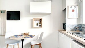 Une cuisine moderne avec un coin repas, un téléviseur à écran plat, une bouteille de vin encadrée et un élément décoratif mural.