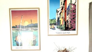 Une pièce avec un mur blanc, une console en bois et deux tableaux encadrés représentant des paysages côtiers.