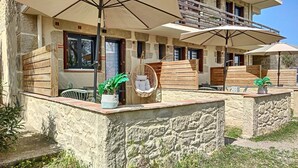 A stone building with outdoor seating, umbrellas, and a hanging chair. - Studio Terrasse « Louille » Vue sur le Parc Nature 5min Plages Argelès-sur-mer (Argeles-Sur-Mer)