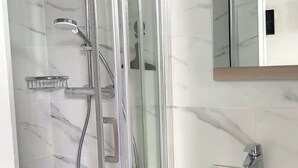 A modern bathroom with a glass-enclosed shower, a white sink, and a wooden vanity. - Studio Terrasse « Louille » Vue sur le Parc Nature 5min Plages Argelès-sur-mer (Argeles-Sur-Mer)