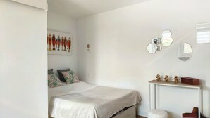 Une chambre à coucher comprenant un lit, une table de chevet agrémentée d’objets décoratifs, un miroir fixé au mur et une œuvre d’art murale.