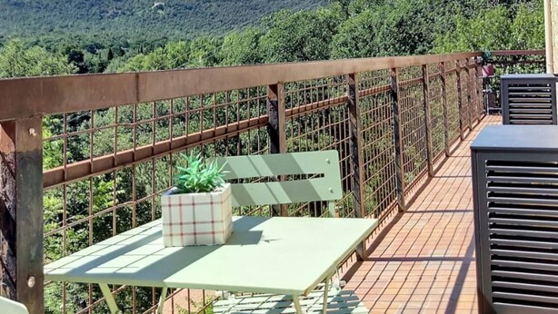 Una terraza con vistas a montañas, una mesa con sillas y una planta en maceta.