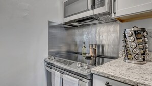 Une cuisine moderne équipée d’une cuisinière en acier inoxydable, d’un four à micro-ondes et d’un étagère à épices dotée de plusieurs compartiments.