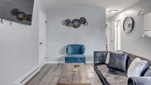 Un salon moderne avec un fauteuil bleu, un canapé gris foncé et une table basse en bois.