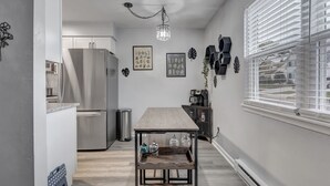 Une cuisine moderne avec une table en bois, des appareils électroménagers en acier inoxydable et des œuvres d’art décoratives accrochées au mur.