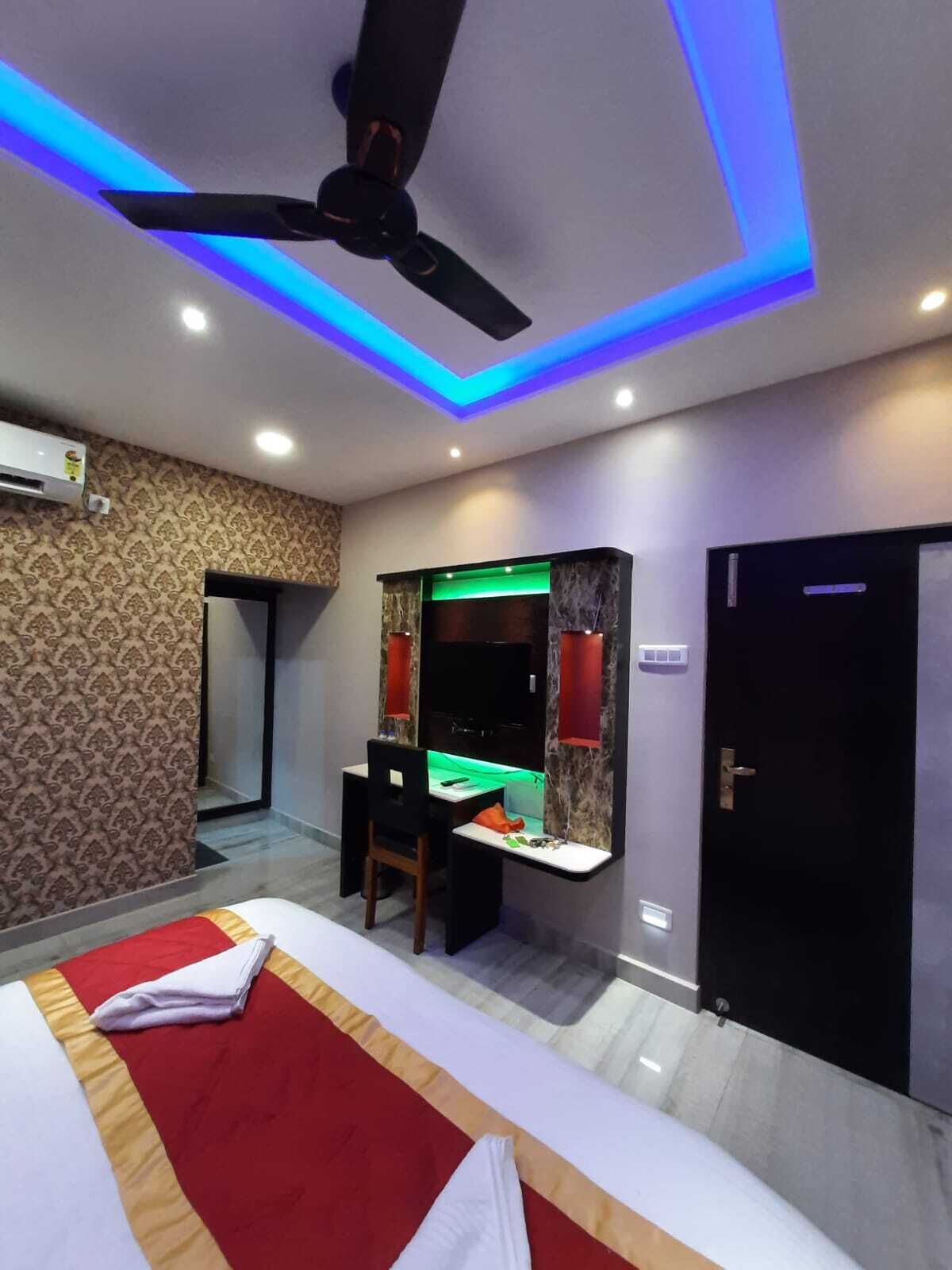 Una habitación de hotel con cama, escritorio, silla y ventilador de techo.