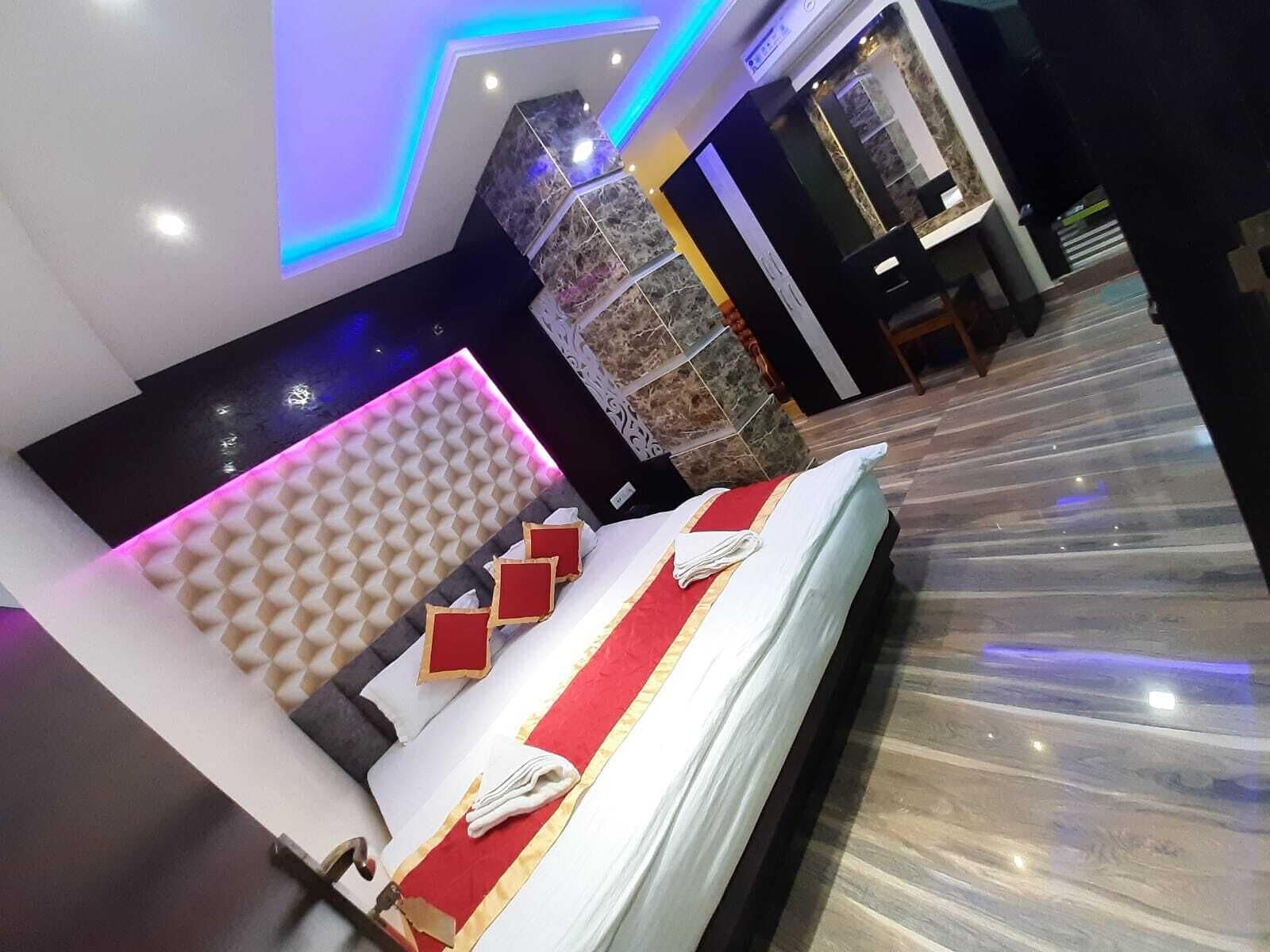 Habitación de hotel moderna con una cama grande, suelo de mármol y un diseño de techo único con iluminación azul.
