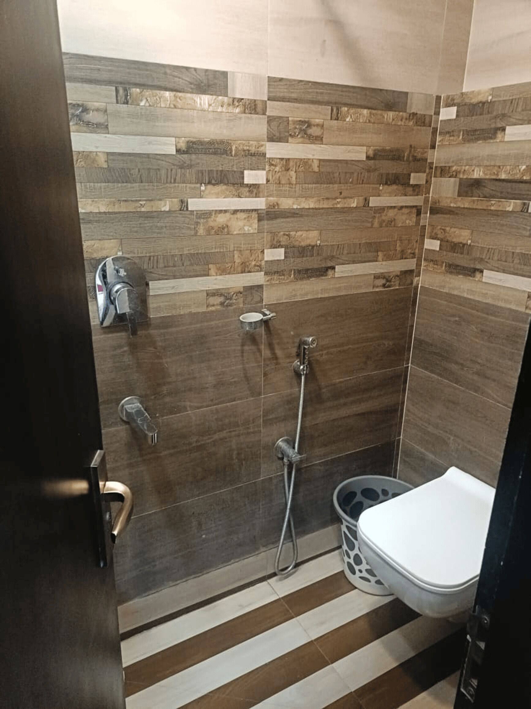 A bathroom with a shower, toilet, and a trash bin.