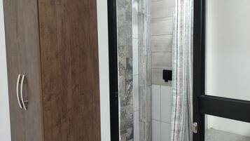 Une pièce avec une armoire en bois, un espace douche doté d’un rideau à rayures et un sol carrelé.