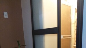 A hallway with a potted plant, a sliding door, and a shower area. - Chakana Family Home (Callao)