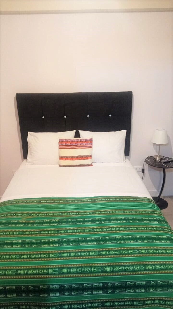 A bed with a dark headboard, white pillows, and a green patterned bedspread.