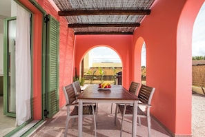 A dining area with a table and chairs, a fruit bowl, and a view through an archway. - Villa Selene in Gennadi (Γεννάδι)