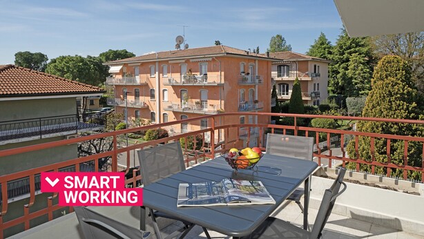 Un balcon avec une table, des chaises et un saladier rempli de fruits.