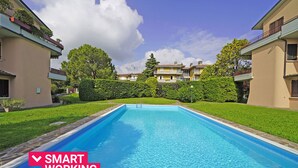 Une piscine entourée de pelouses bien entretenues et d’immeubles dotés de balcons.