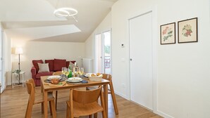 Un coin repas avec une table et des chaises en bois, un canapé rouge et une lampe en arrière-plan.