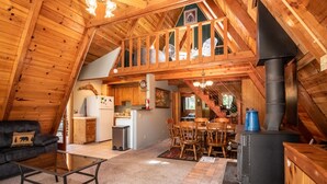 Accogliente interno di una baita in legno con zona pranzo, angolo cottura e camino.