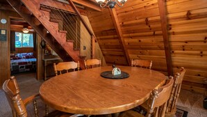 Un tavolo da pranzo in legno con sei sedie, un lampadario e una scala che conduce a una zona mansardata.