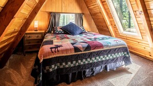 Una camera da letto mansardata accogliente con un letto grande, un comodino e una finestra con tende.