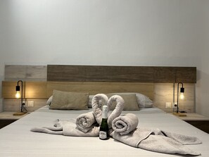 Ein ordentlich bezogenes Bett mit Handtüchern, einer Weinflasche und zwei Lampen auf Nachttischen.