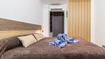 A hotel room with a wooden headboard, a bed with brown bedding, a blue towel, and a bottle of champagne.