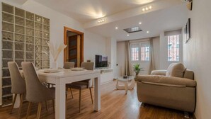 Una sala de estar moderna con comedor, un sofá y un televisor.