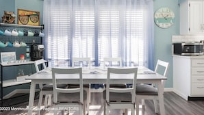 A dining area with a white table and chairs, a kitchen with a microwave, and a clock on the wall. - Family Fun!! 2 Blocks to Famous Boardwalk & Beach. 3Br/2Fb. 4 Adults + Kids (Seaside Heights)