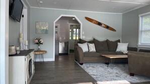 A modern living room with a sofa, coffee table, and a skateboard mounted on the wall.
