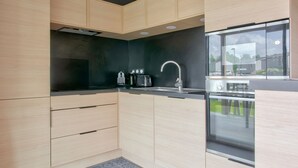 A modern kitchen with light wood cabinets, a black countertop, and a stainless steel sink. - Chalet for 4, terrace & heated pool (Pont-l´Abbé)