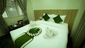 A hotel room with a neatly made bed, a bedside table with a lamp, and a window with curtains. - Hotel Namaskar (Kathmandu)