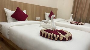 A hotel room with two beds, each with white bedding and maroon pillows. There is a decorative swan towel on the beds. - Hotel Namaskar (Kathmandu)