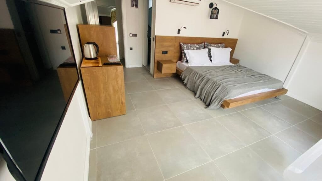 A bedroom with a bed, bedside table, and a wooden dresser.