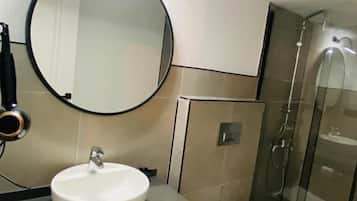 Een moderne badkamer met een ronde spiegel, een witte wastafel, een toilet en een douchecabine van glas.