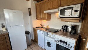 A compact kitchen with a refrigerator, dishwasher, washing machine, oven, microwave, and a coffee maker. - Les Granges 13, 6-8 person 50m from the slopes (Plagne Montalbert)