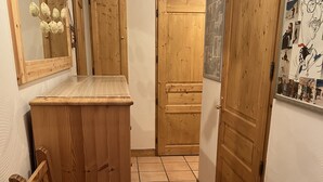 A narrow hallway with wooden doors, a tiled floor, and a small wooden bench with a cushion. - Les Granges 13, 6-8 person 50m from the slopes (Plagne Montalbert)