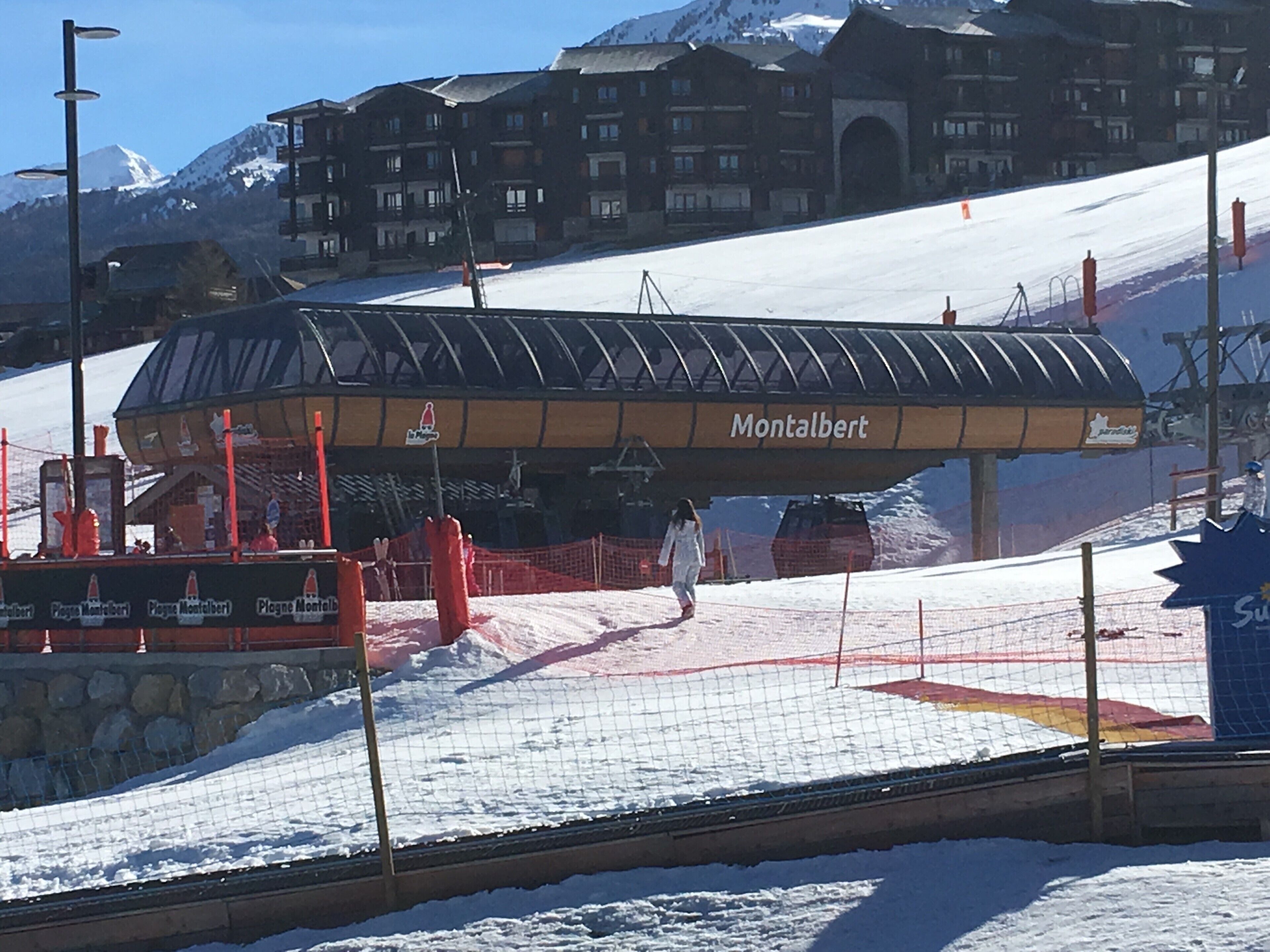 Een liftstation voor skiliften, met een beschutte ruimte met de naam 'Montalbert' en een besneeuwde helling op de achtergrond.