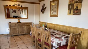 Un comedor con una mesa y sillas de madera, un armario de madera y un espejo con adornos de corazón.