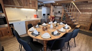 A modern kitchen with wooden cabinetry, a dining table set for six, and a staircase leading to a loft area. - La Dorbluche duplex apartment 10-11 person, 2km from the slopes (Aime-la-Plagne)
